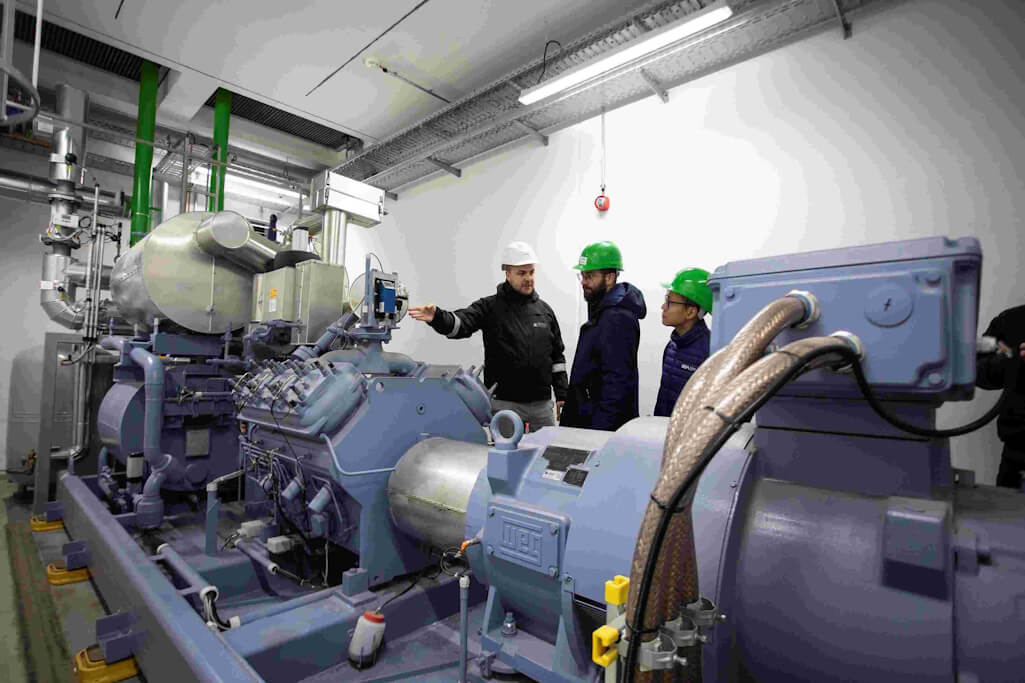 Tim Fiedler, Project Management, Control & Permits Neukoelln CHP Plant, Tim Lennart Scheuermann, GEA Sales Support Engineer and Jiayi Ding, GEA Sales Application Engineer (from left to right) talk about the RedGenium large heat pump. Photocourtesy of GEA/ Cem Yücetas.